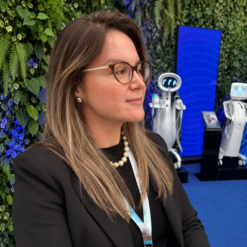 Priscila Favaro de óculos, com equipamentos de estética ao fundo
